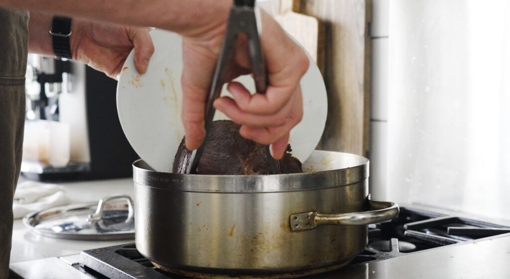 Placing the browned piece of beef in the rondeau pot