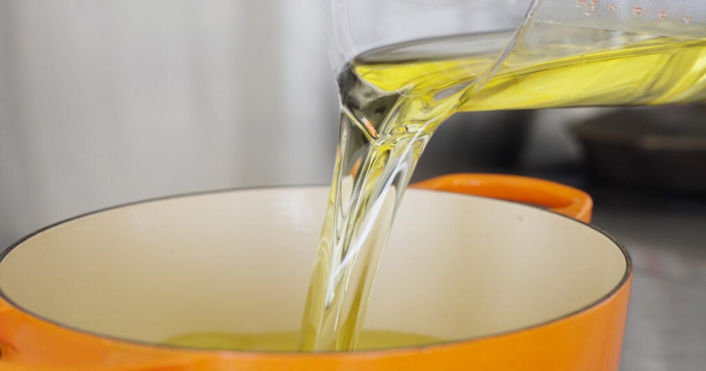 Pouring oil into a large orange pot