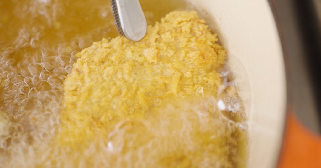 Close up of a piece of breaded pork in oil