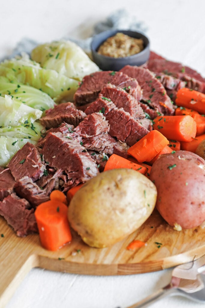 bread board full of cooked potatoes, carrots, cabbage, and corned beef
