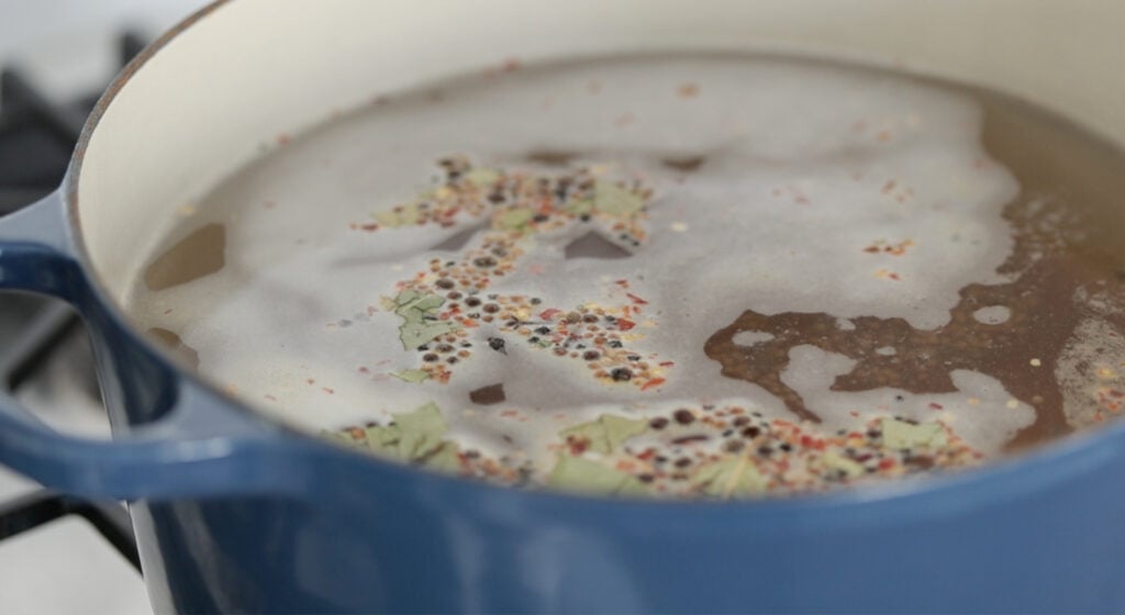 boiling together water, salt, and pickling spice together in a pot