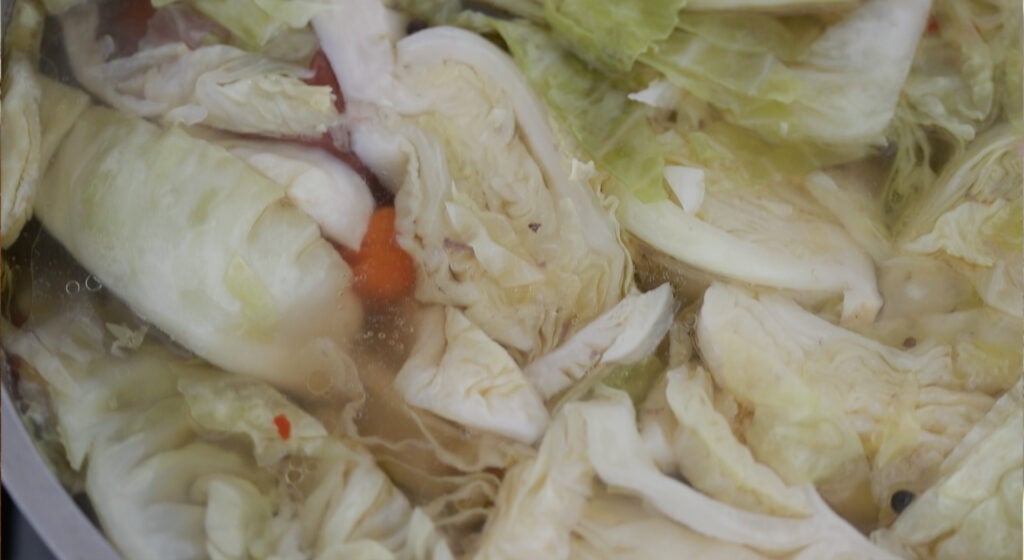 cooked cabbage and vegetables with corned beef in a pot