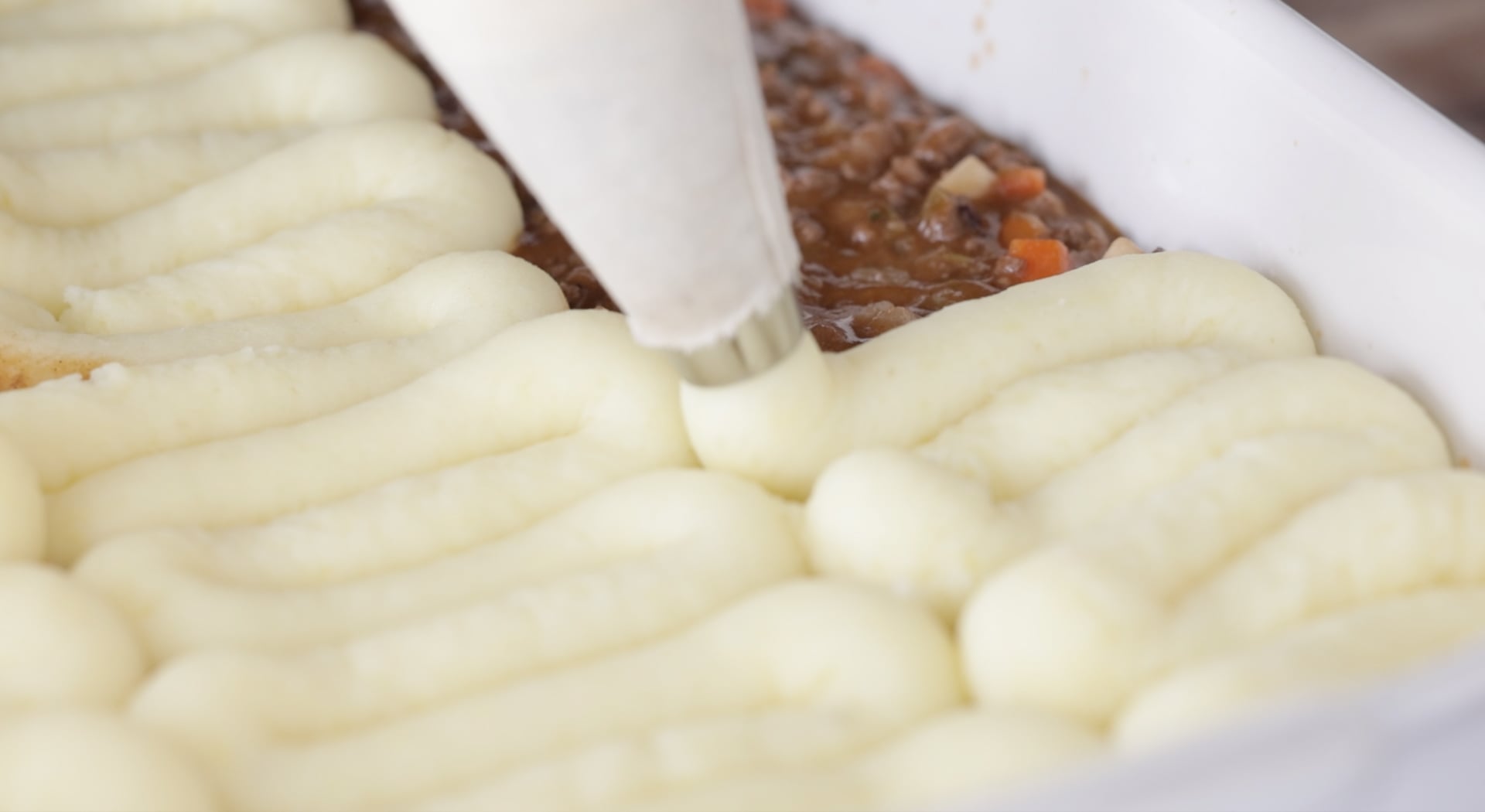 piping potatoes onto cottage pie filling