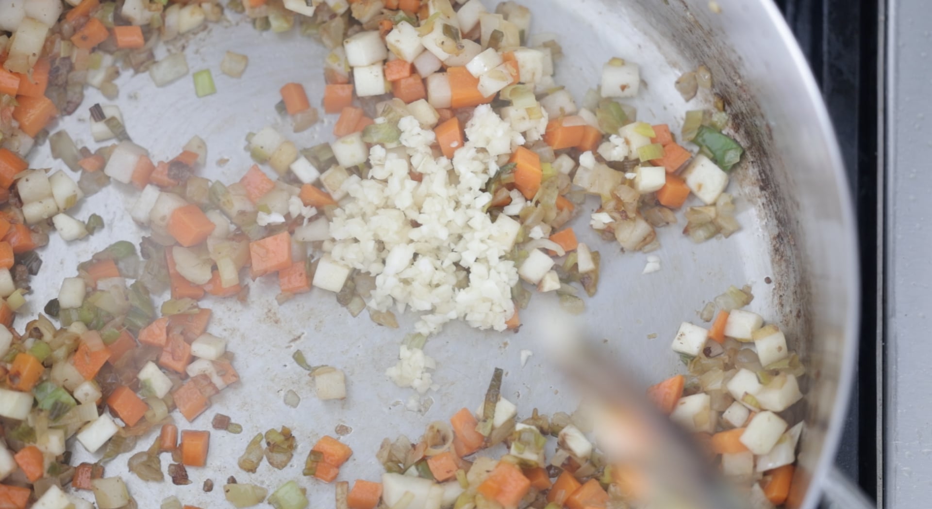adding garlic to cooked vegetables
