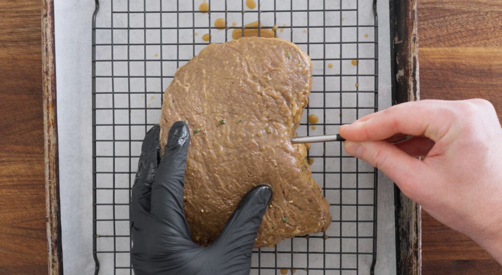 Inserting a thermometer into the side of the beef