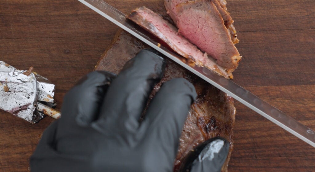 Slicing the cut of beef on a wooden cutting board