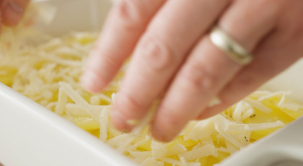 Chef hand adding more cheese to layers