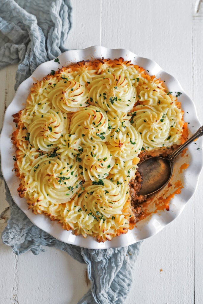 shepherd's pie in a white casserole dish with parsley