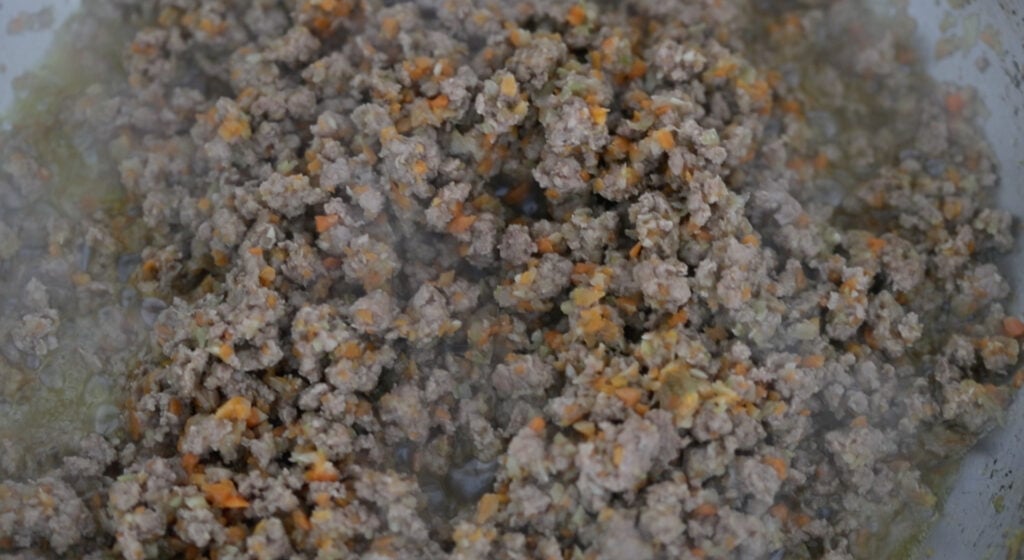 cooking ground lamb with mirepoix in a pan