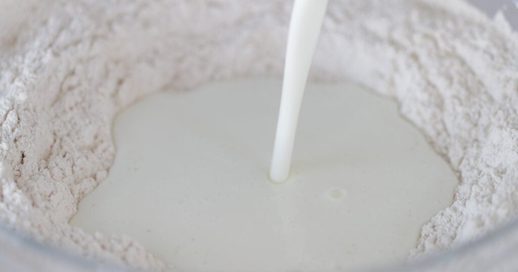 pouring milk into a well of flour