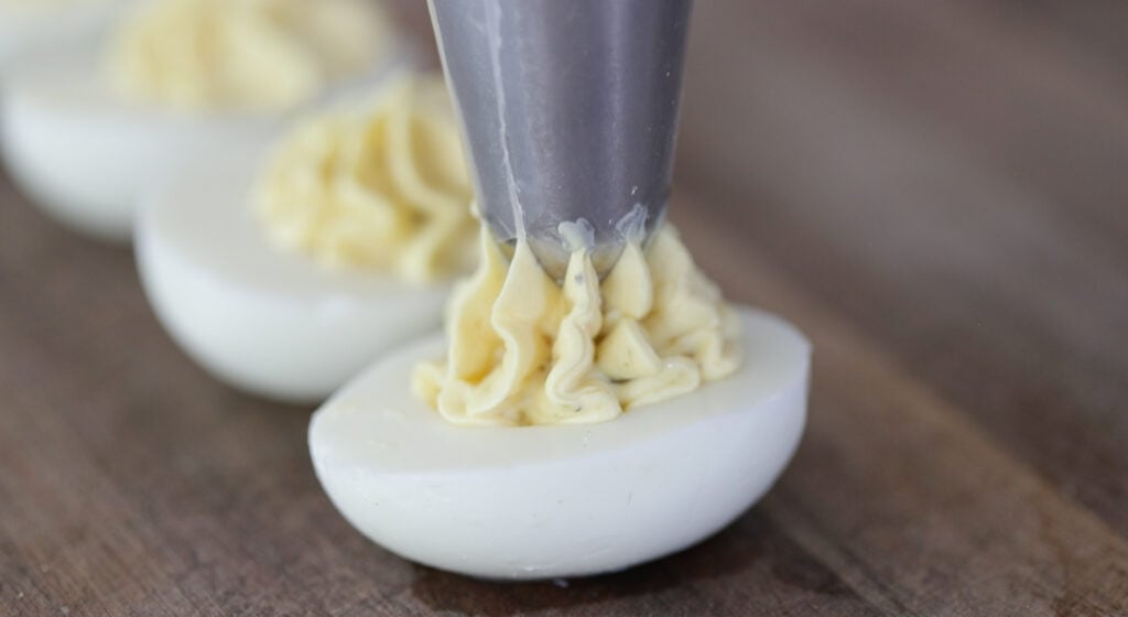 piping southern deviled egg filling into an egg
