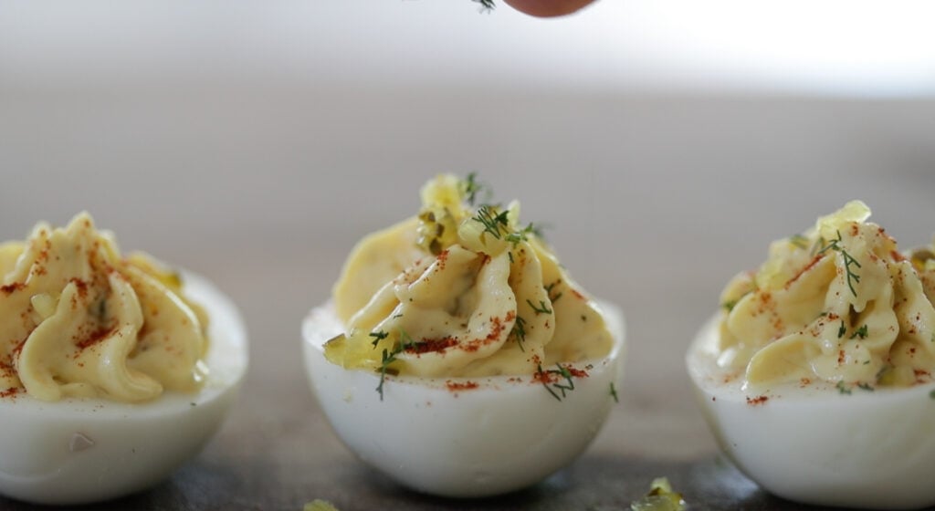garnishing a southern deviled egg with sweet pickles and dill