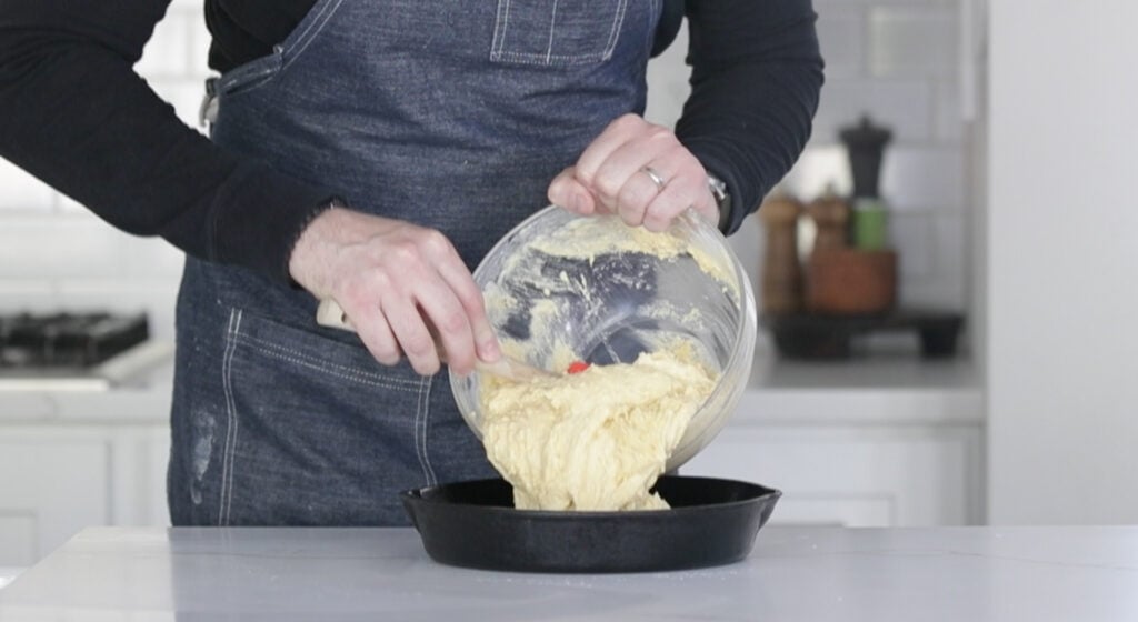 pouring southern cornbread batter into a cast-iron skillet