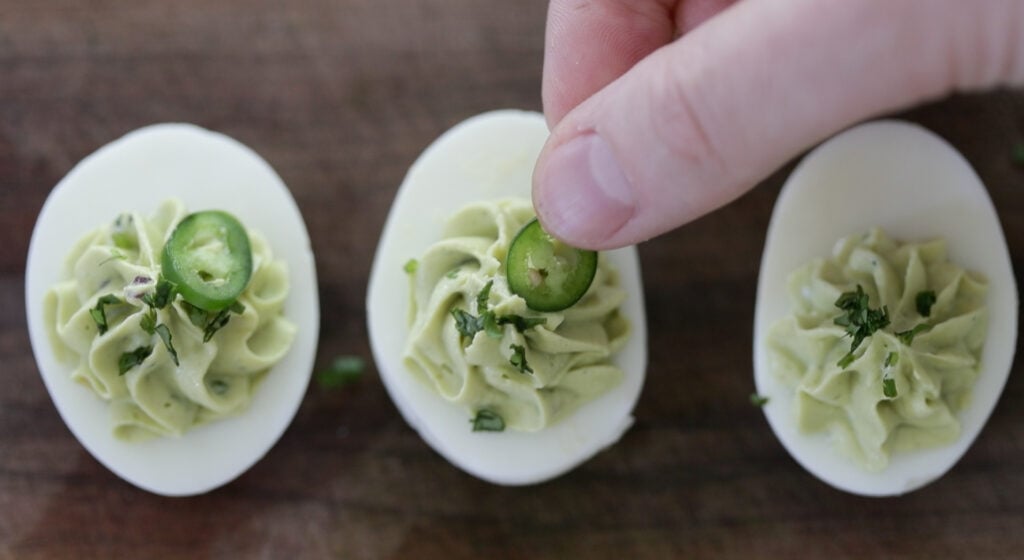 adding sliced jalape&ntilde;os to avocado deviled eggs