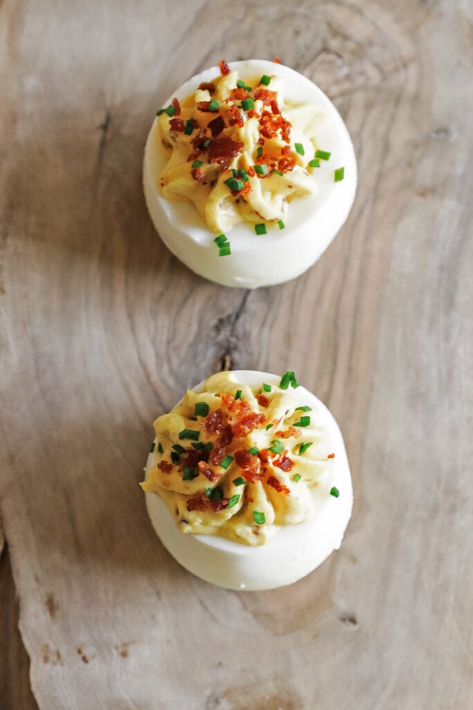 garnishing a deviled egg with bacon and chives
