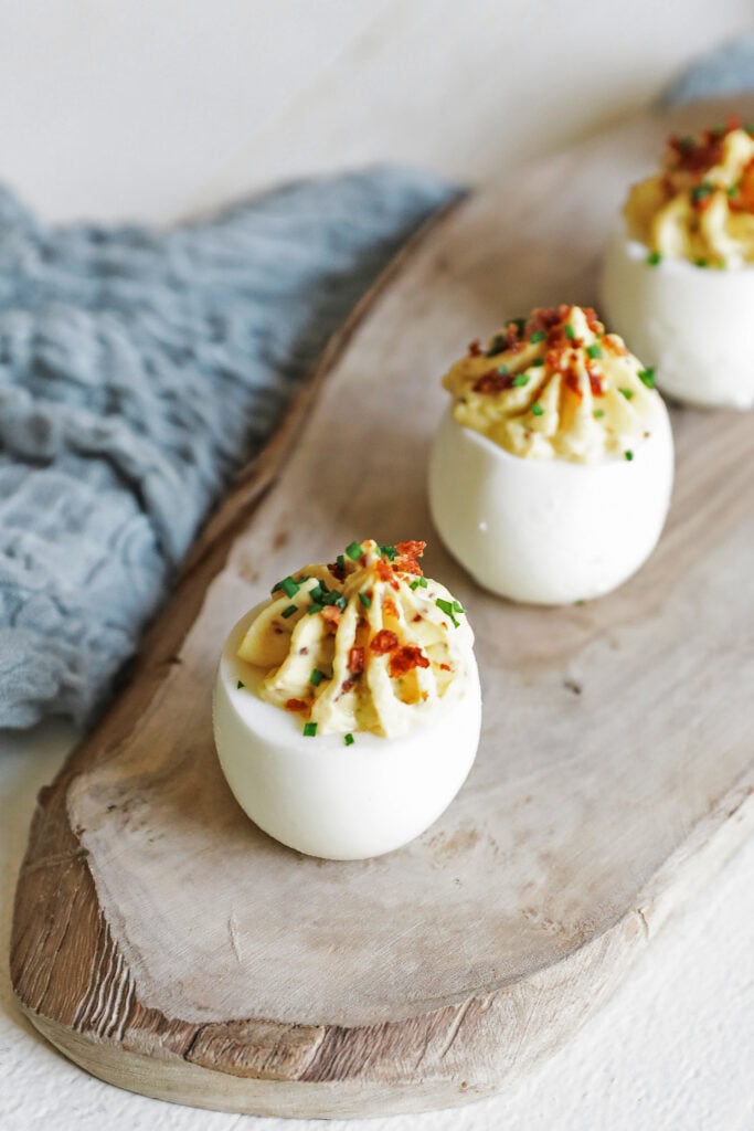 garnishing a deviled egg with bacon and chives