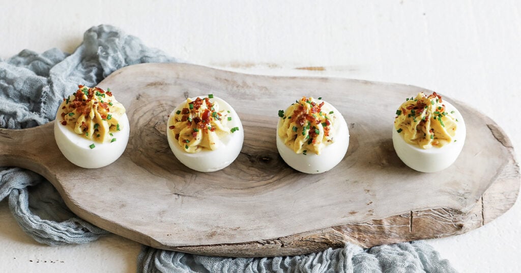 garnishing a deviled egg with bacon and chives