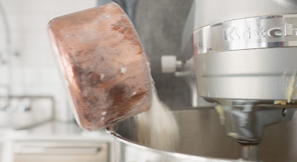 Pouring dry ingredients into bowl of mixer