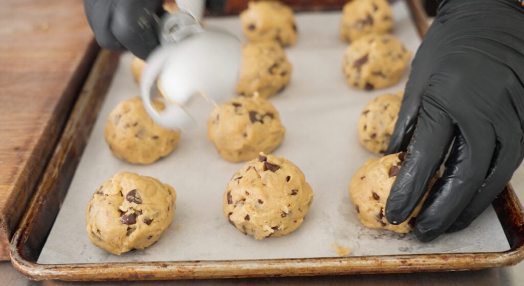 Balls of cookie dough in rows on parchment paper lined cookie sheet