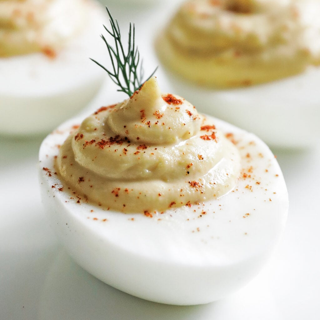 deviled eggs on a plate with paprika and dill
