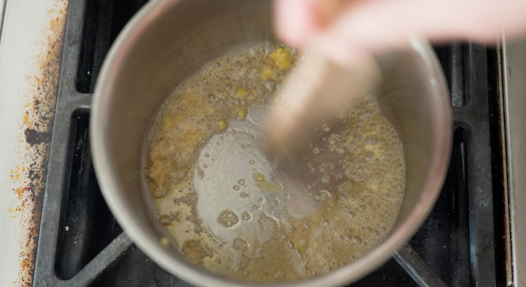 Saucepan on the stove with garlic and ginger bubbling in the bottom