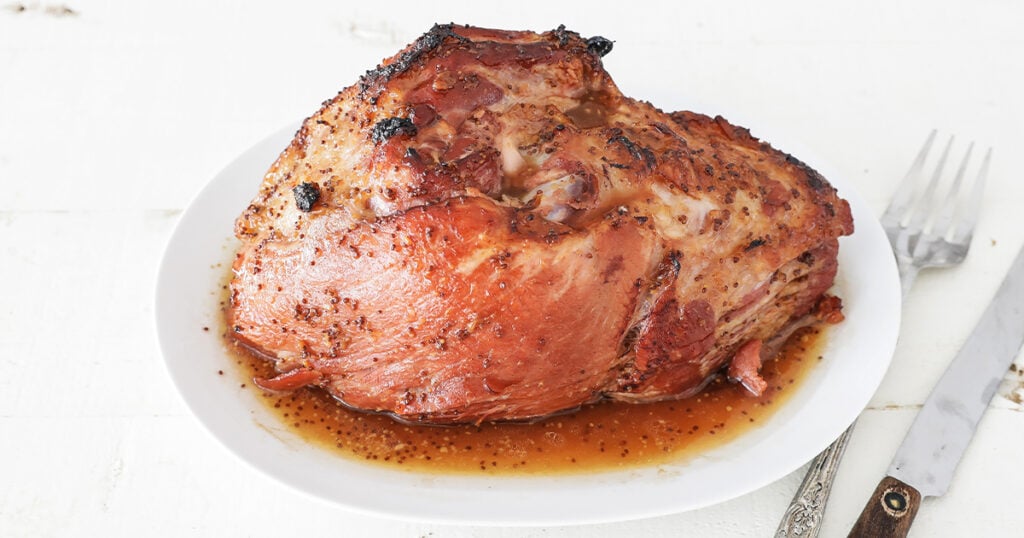 glazed ham resting in a pan with juices