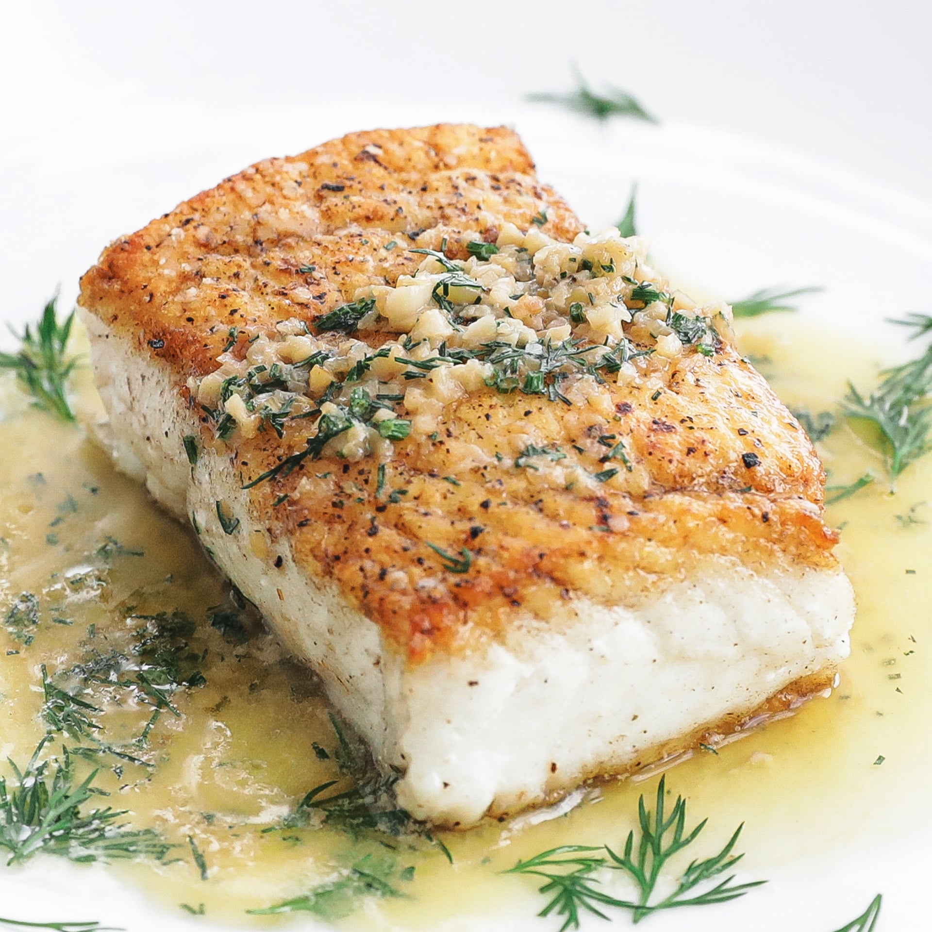 halibut on a plate with butter dill sauce