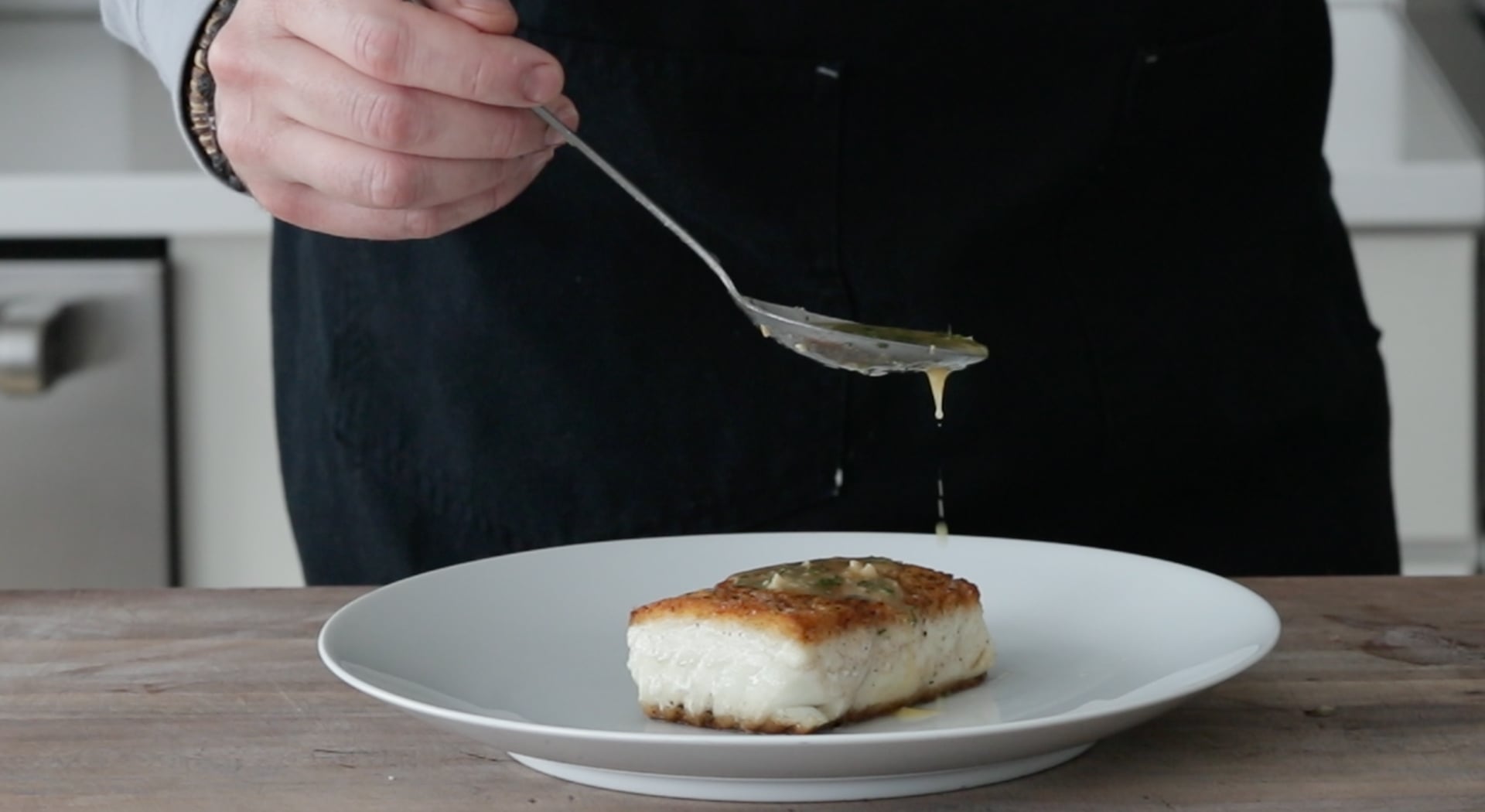 pouring a lemon butter sauce over halibut