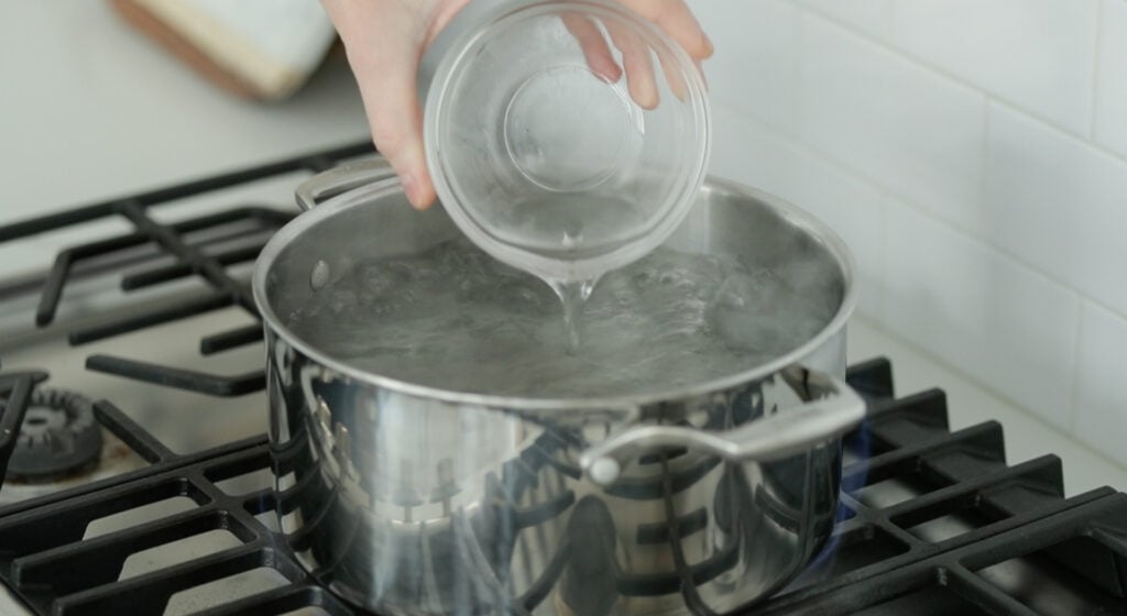 adding vinegar to a pot of boiling water