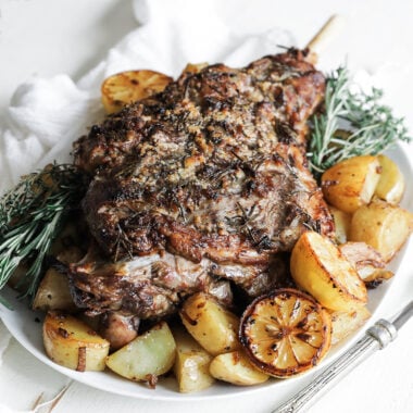a roasted leg of lamb with lemons and potatoes
