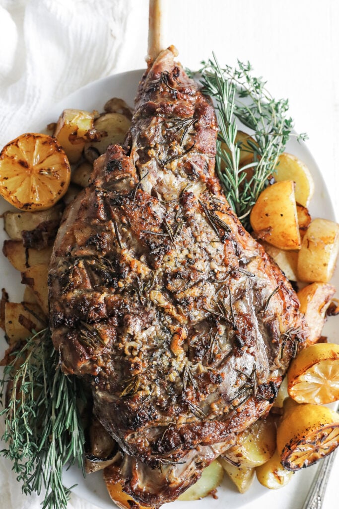 a roasted leg of lamb with lemons and potatoes