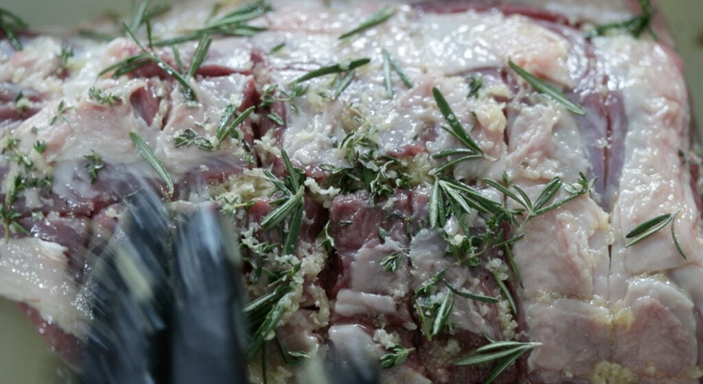 coating a leg of lamb in herbs and garlic