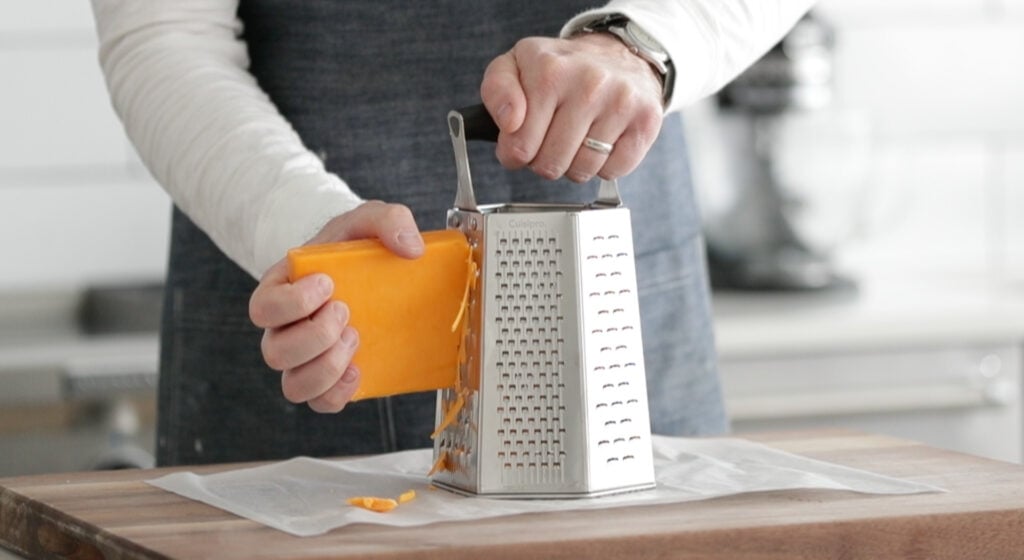 grating cheddar cheese on a cheese grater