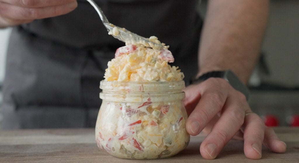 Spooning the pimento cheese dip into a jar for serving. 