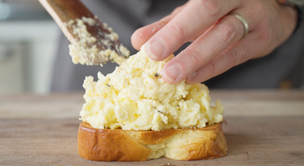 Scooping scramled eggs onto a piece of toast