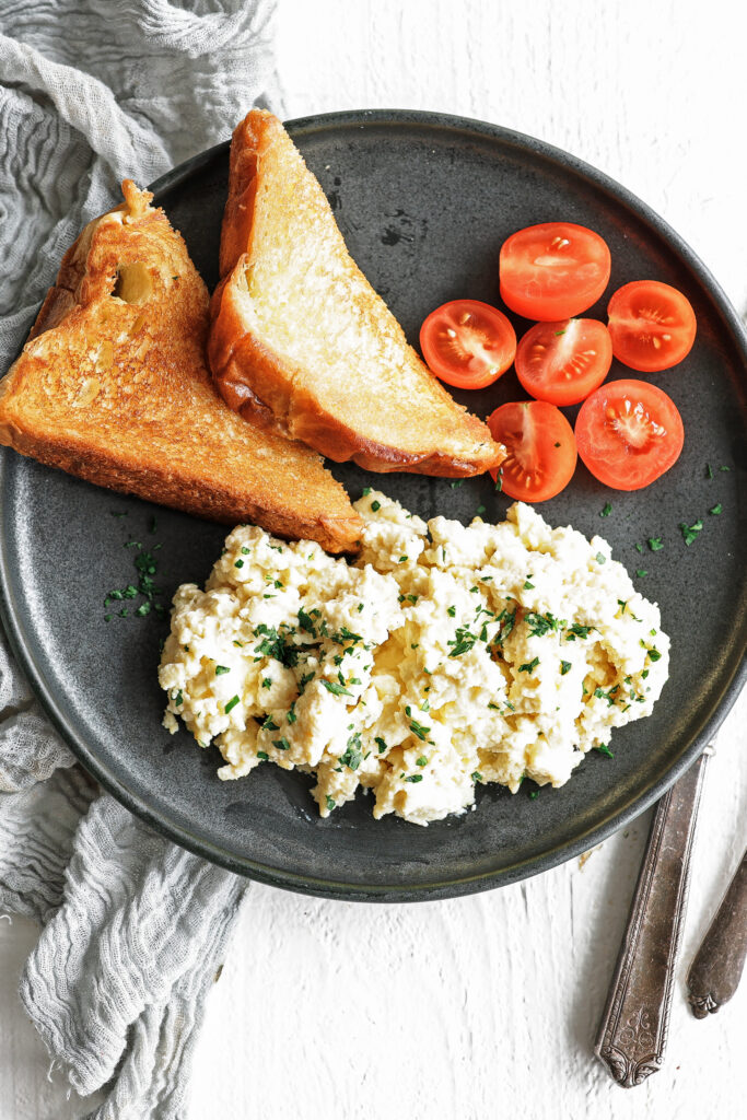 scrambled eggs on a plate with toast and tomatoes