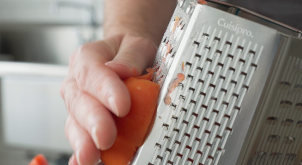 Using a box grater to grate a tomato