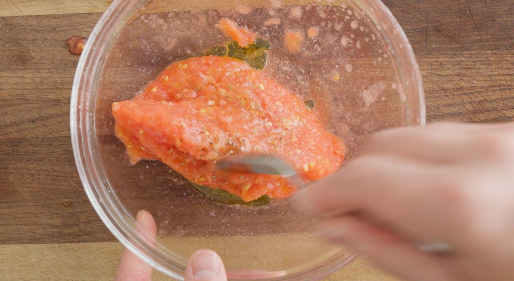 Using a spoon to stir the ingredients in a glass bowl