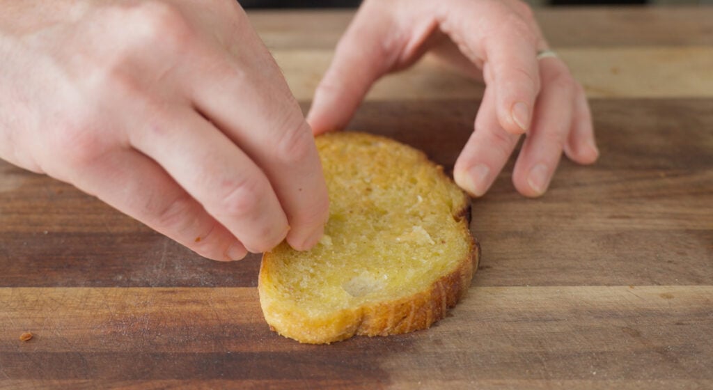 Rubbing garlic cloves on a slice of toast