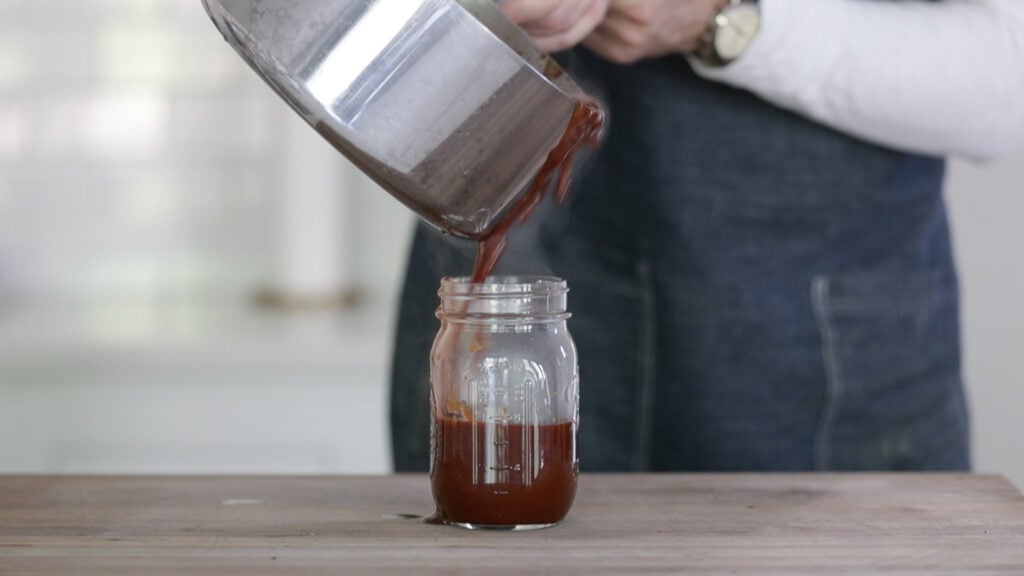 pouring bbq sauce in a jar