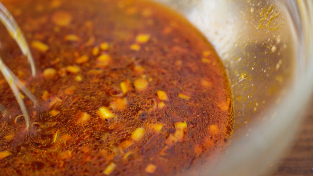 whisking marinade ingredients in a bowl
