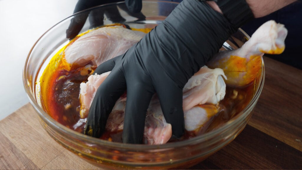 Moving chicken pieces around in the bowl of marinade