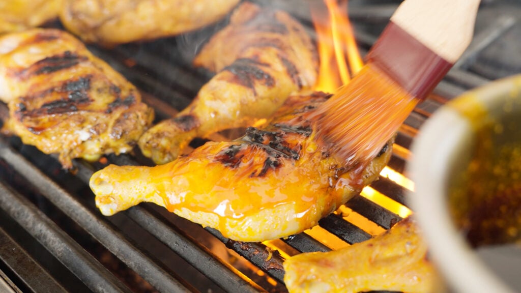 Using a basting brush to add sauce to chicken