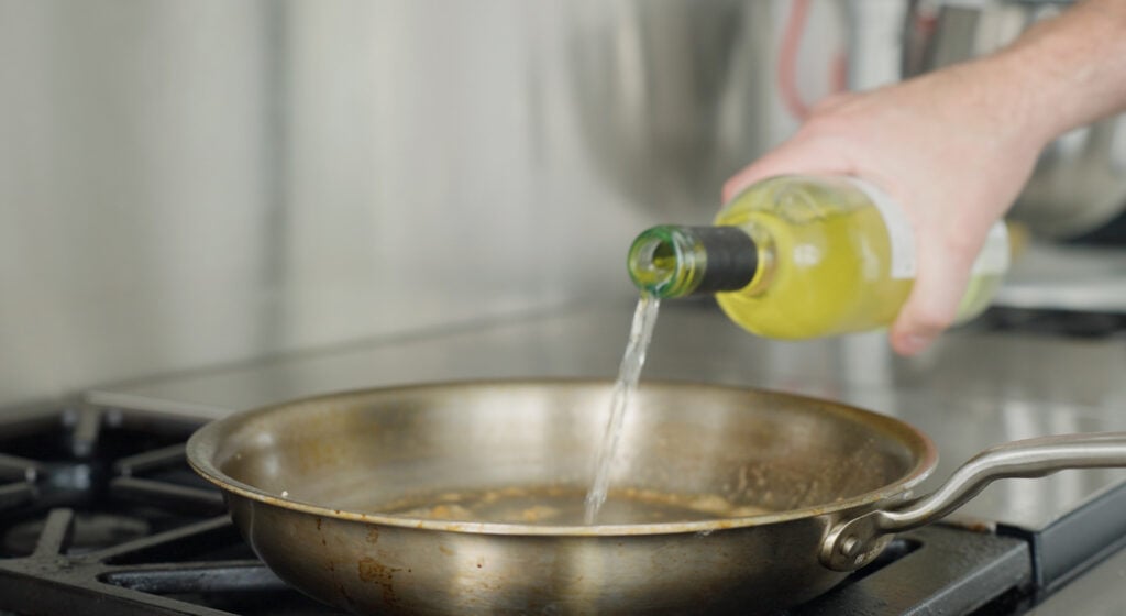 Pouring white wine into the pan 