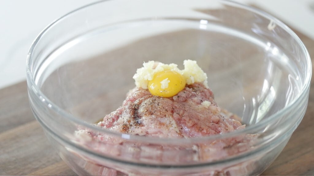 mixing chicken in a bowl with eggs