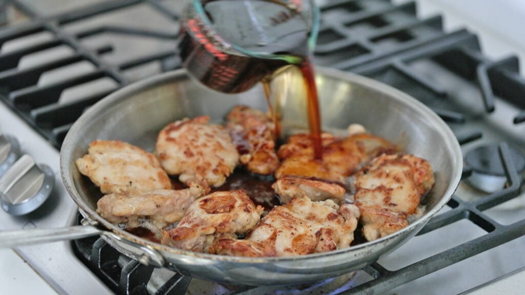 adding teriyaki sauce to cooked chicken