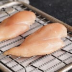 Two chicken breasts ona rack over a sheet tray