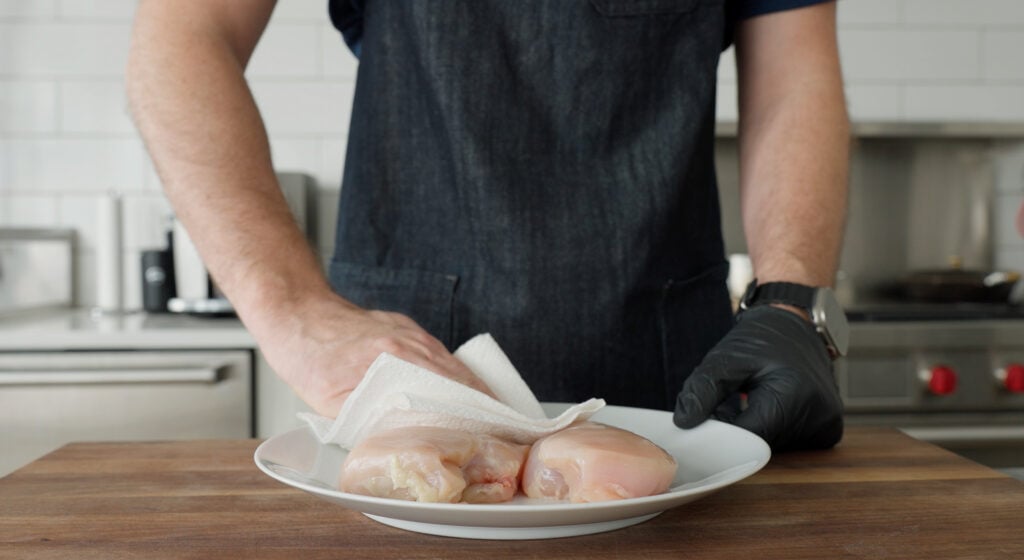 Patting chicken dry with a paper towel