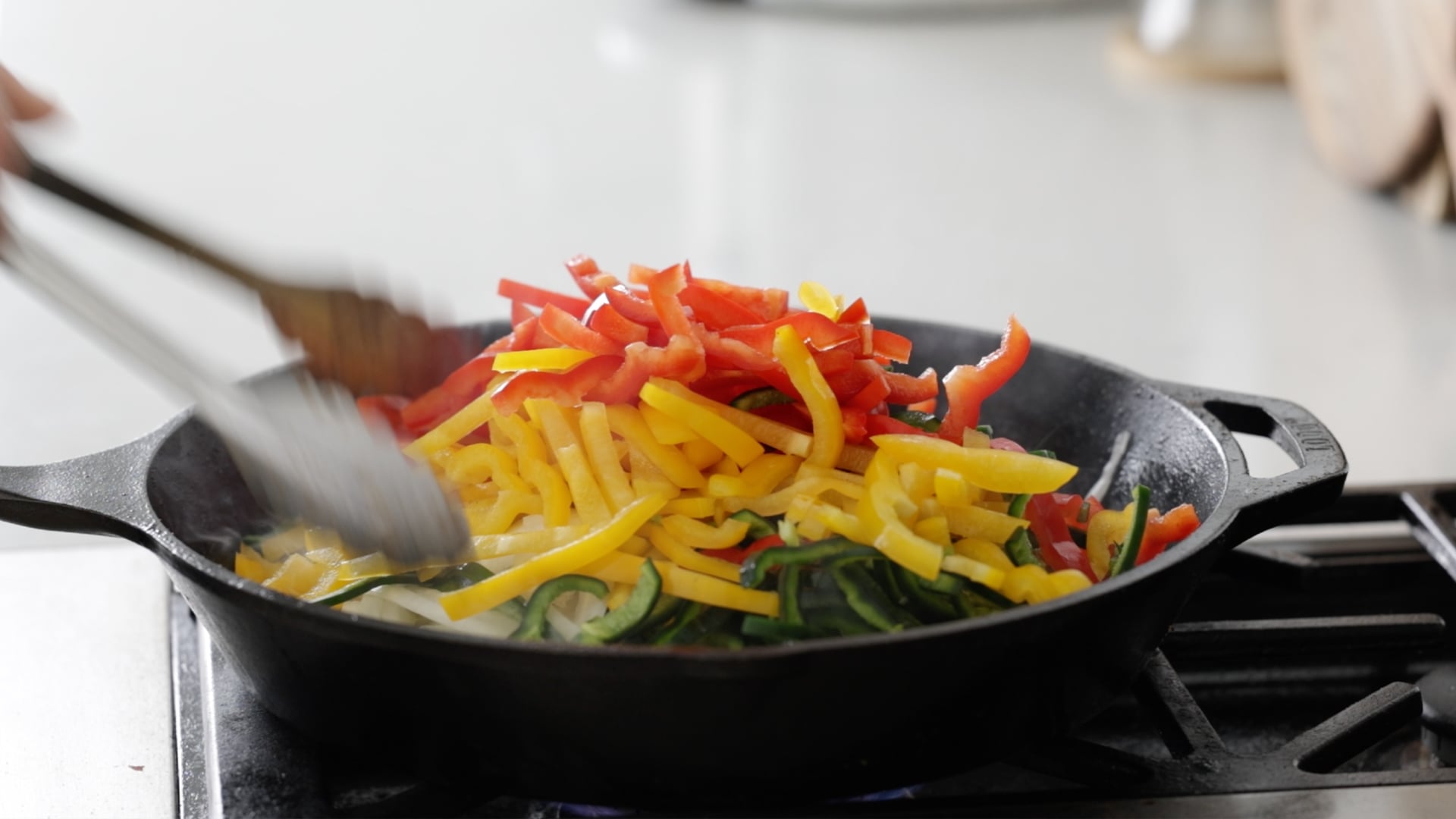 adding peppers and onions to a skillet