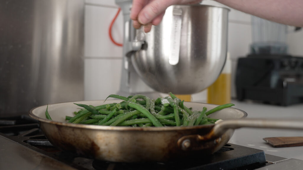Sprinkling salt on the beans in a skillet